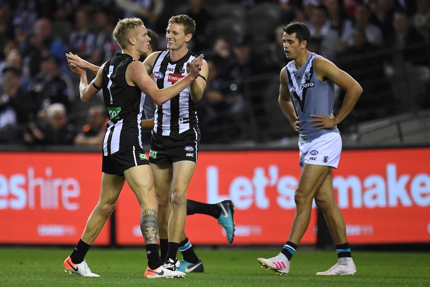 Jaidyn Stephenson and Will Hoskin-Elliott embrace after the Magpies kick a goal against the Power.