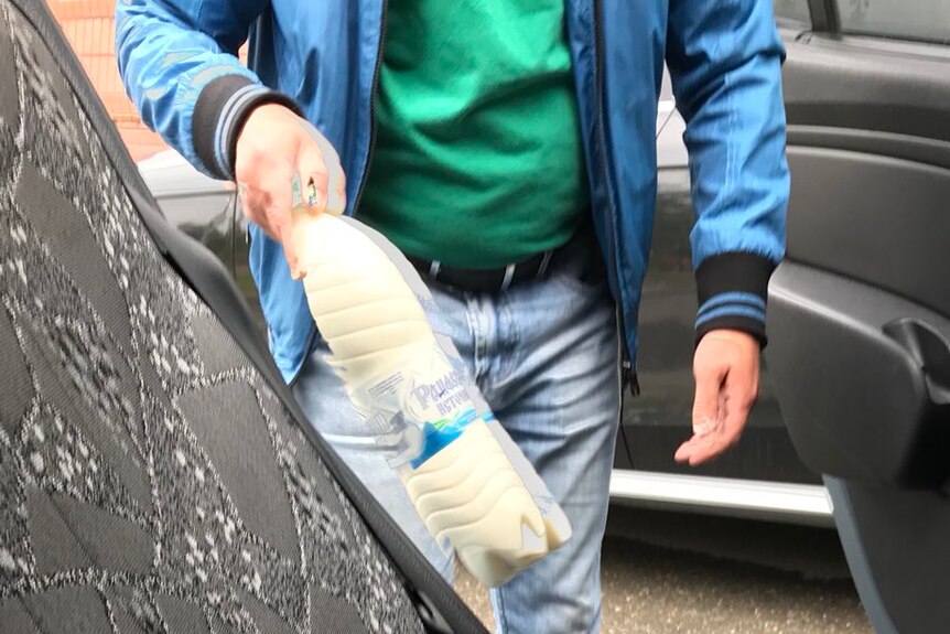 A person holds a bottle of milk found in an Uber in Russia