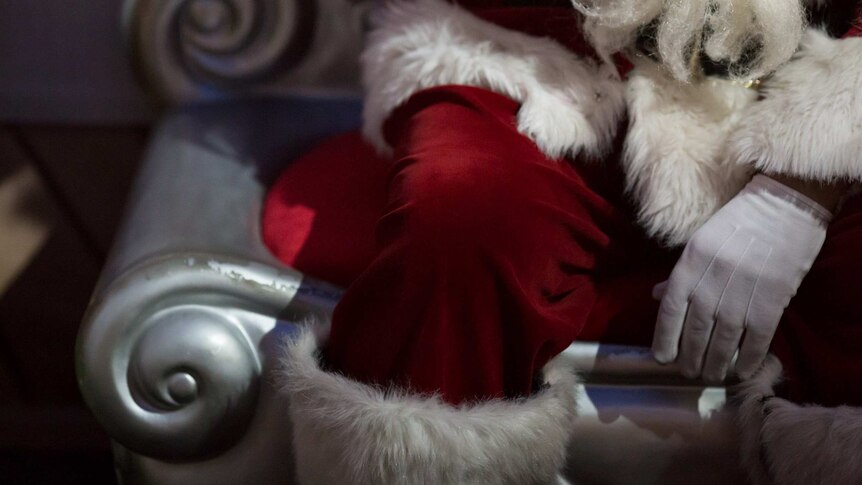Santa's white-gloved hand rests on his red-suited knee