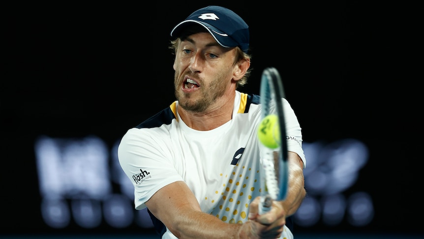 An Australian male tennis player uses a backhand return at the Australian Open.