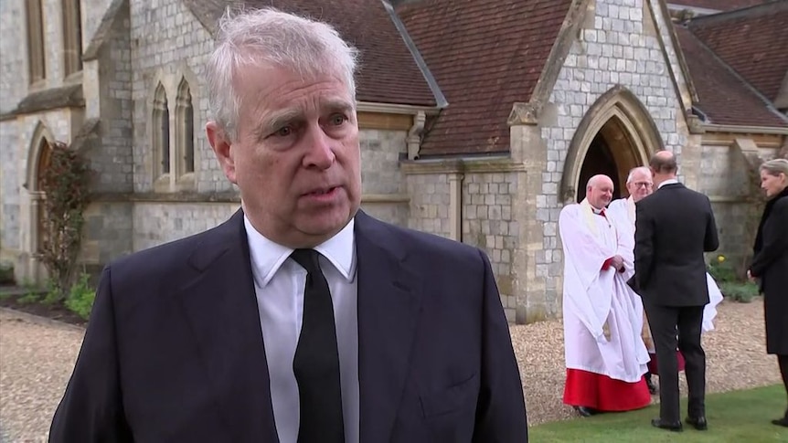 prince andrew talking to camera with church in background