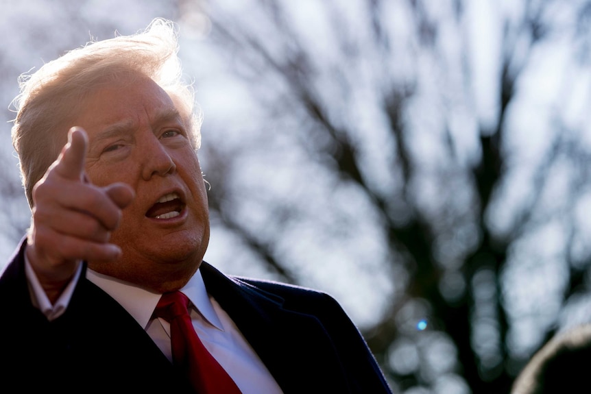 President Donald Trump points his finger as he speaks to reporters