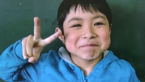 The lost Japanese boy holds up his fingers in a V on Nippon television.