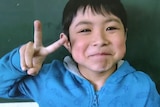 The lost Japanese boy holds up his fingers in a V on Nippon television.