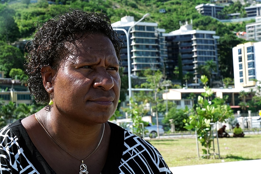 A PNG woman with a city beach backdrop.