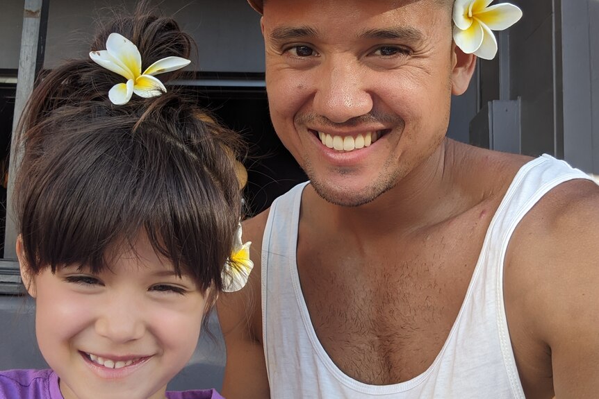 Seiji Armstrong and his daughter with frangipani flowers in their hair.