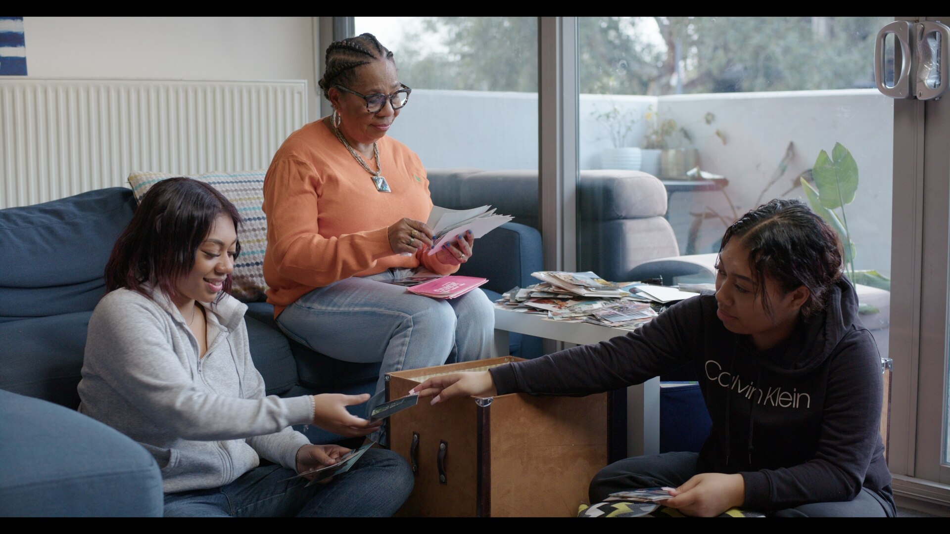 Three women sitting in chairs looks at photographs
