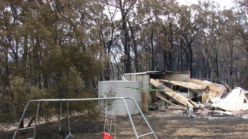 Children's play equipment sits in front of a house destroyed by bushfire of black Saturday.