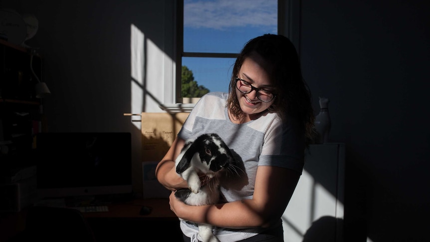 The administrator of a women's support group on Facebook holds a pet rabbit in her home in Kalgoorlie.