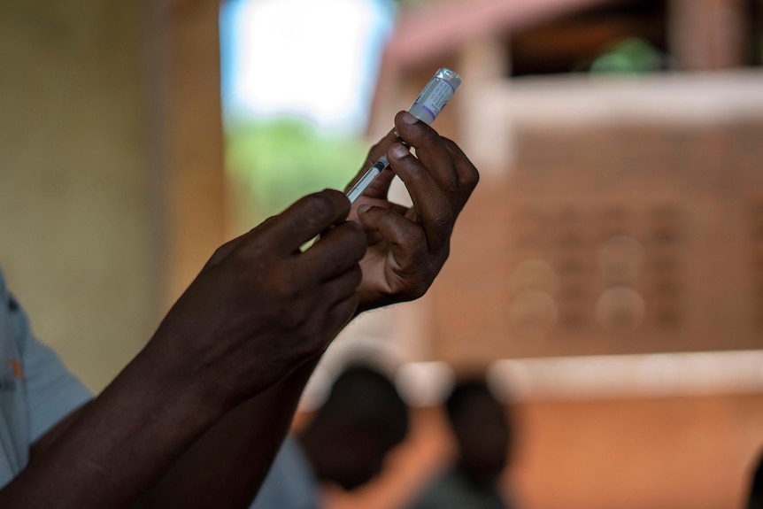 Hands hold a vaccine vial 