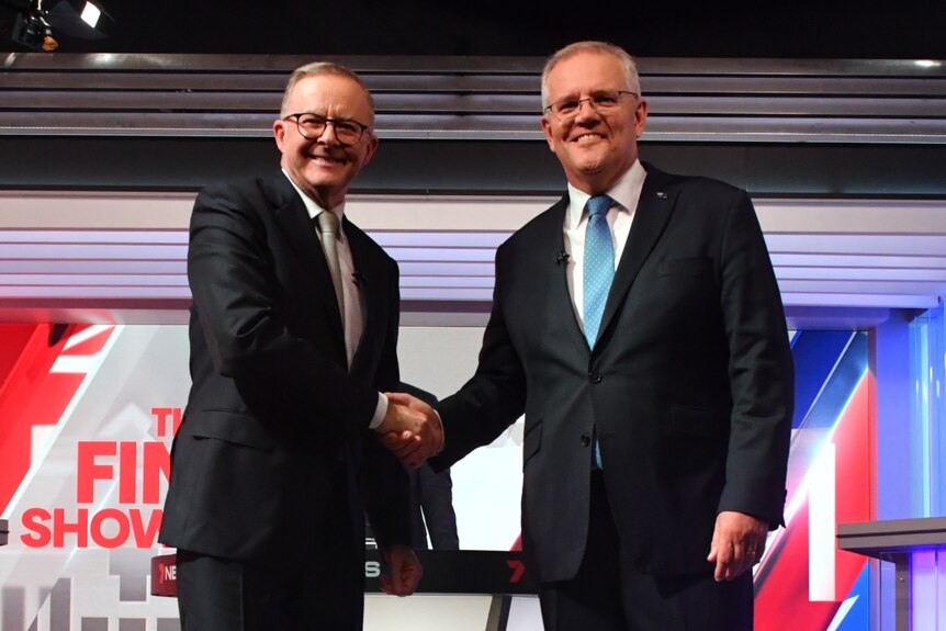 Albanese and Morrison shake hands and smile at the camera. 