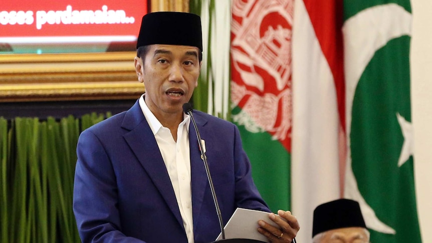 Indonesian President Joko Widodo stands at a lectern talking into a microphone.