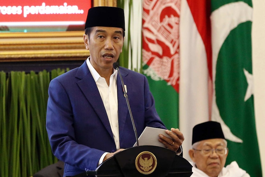 Indonesian President Joko Widodo stands at a lectern talking into a microphone.