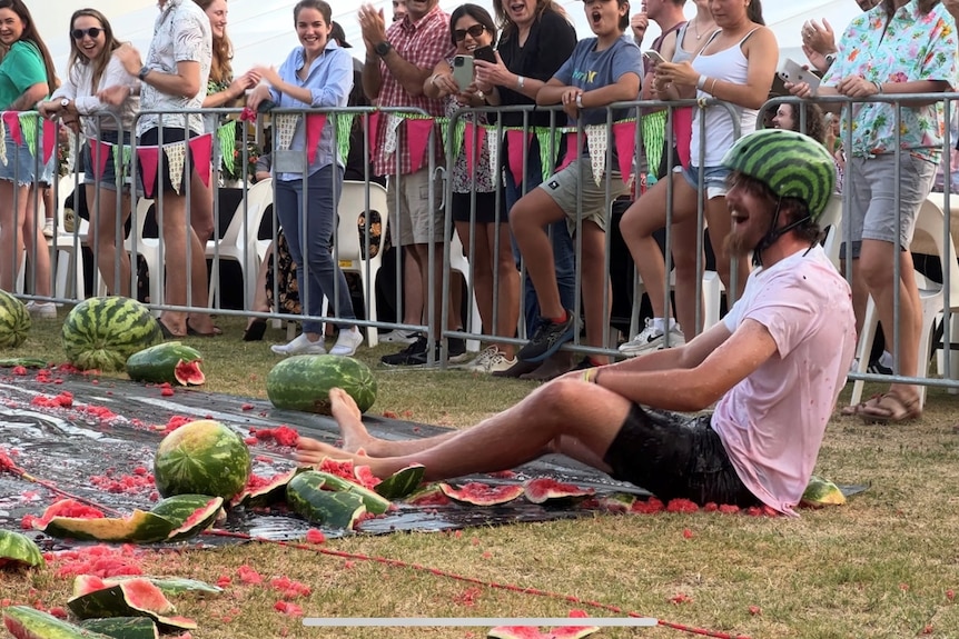 A skier sits on the ground surrounded by smashed watermelons.