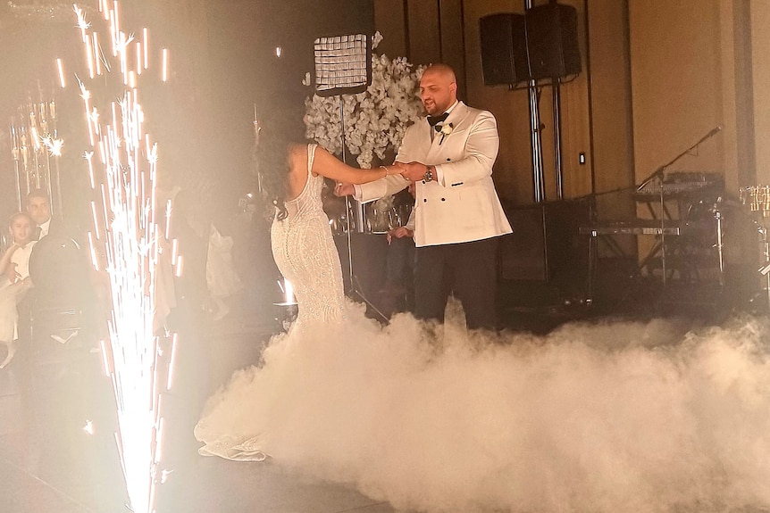 A bride and groom dancing as a roman candle fires sparks into the air.