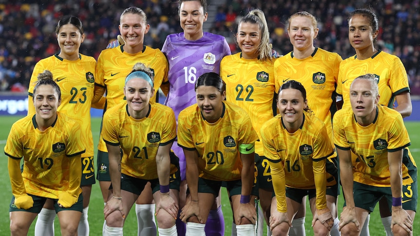 A group of female soccer players pose for a team photo