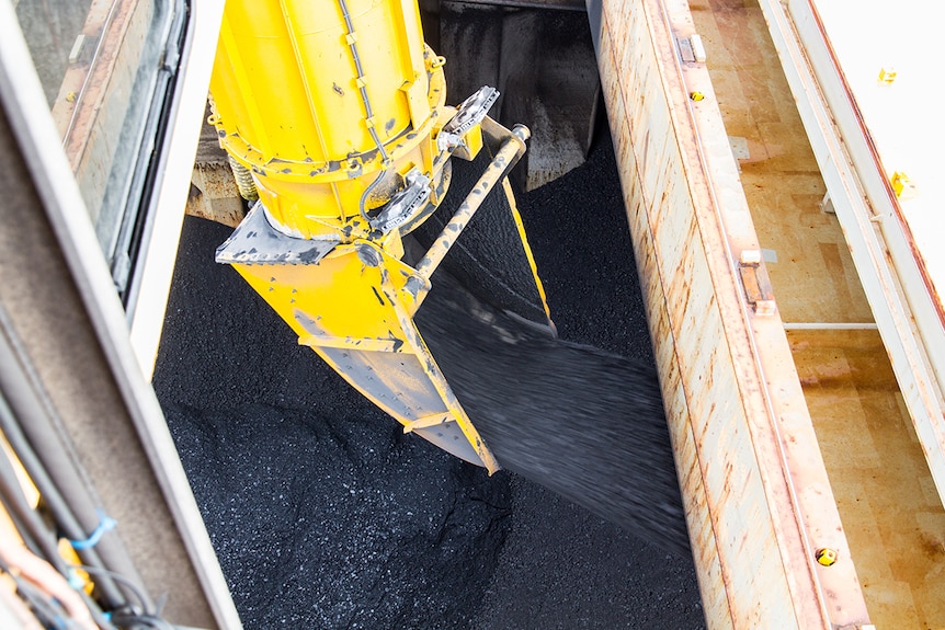 Coal rushes from a scoop into a coal ship's hold.