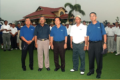 Five men stand together on a golf green.