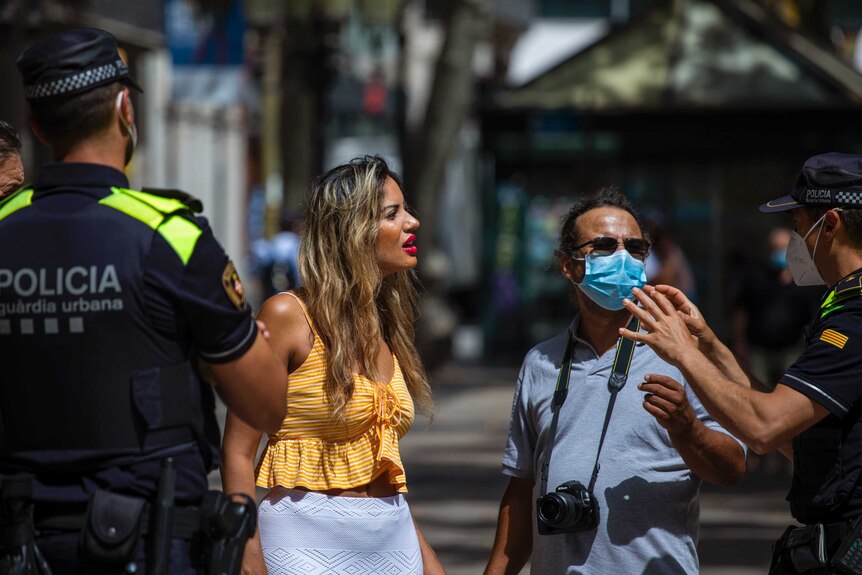 Catalonian police officers tell at a woman that the use of a face mask is mandatory in Barcelona.
