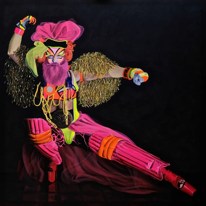 A portrait of a performance artist wearing bold colours and maximalist clothing against a black backdrop.