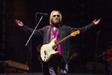 Tom Petty stands with his arms outstreched while perfomring in California.