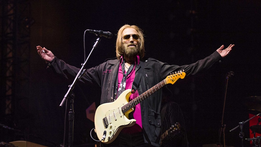 Tom Petty stands with his arms outstreched while perfomring in California.