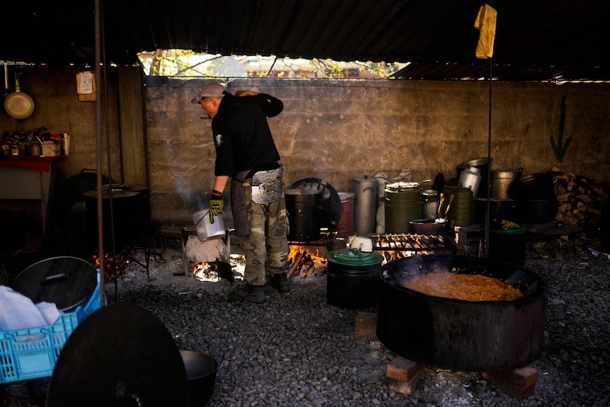 Mężczyzna przygotowujący posiłki w industrialnym środowisku obozowym
