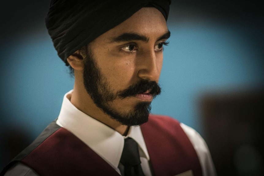 A close up of the actor wearing a traditional sikh turban, a serious look on his face.