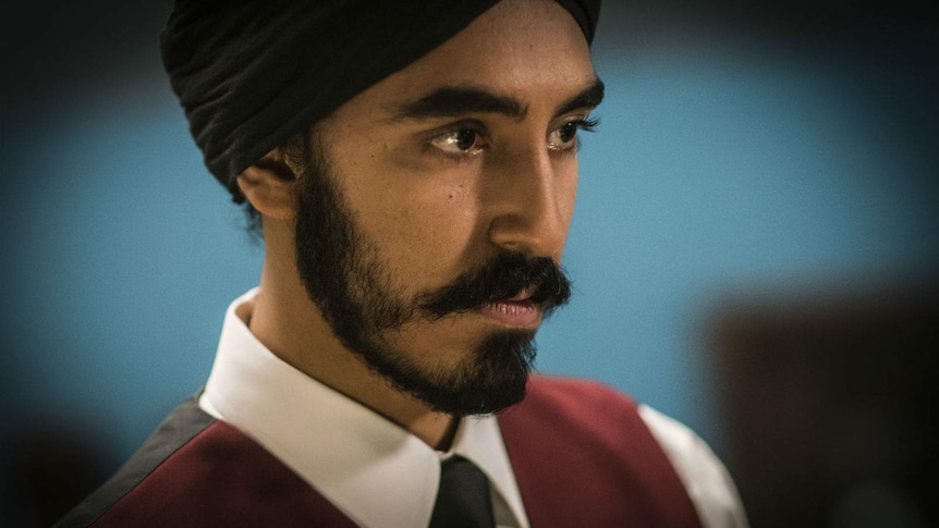 A close up of the actor wearing a traditional sikh turban, a serious look on his face.