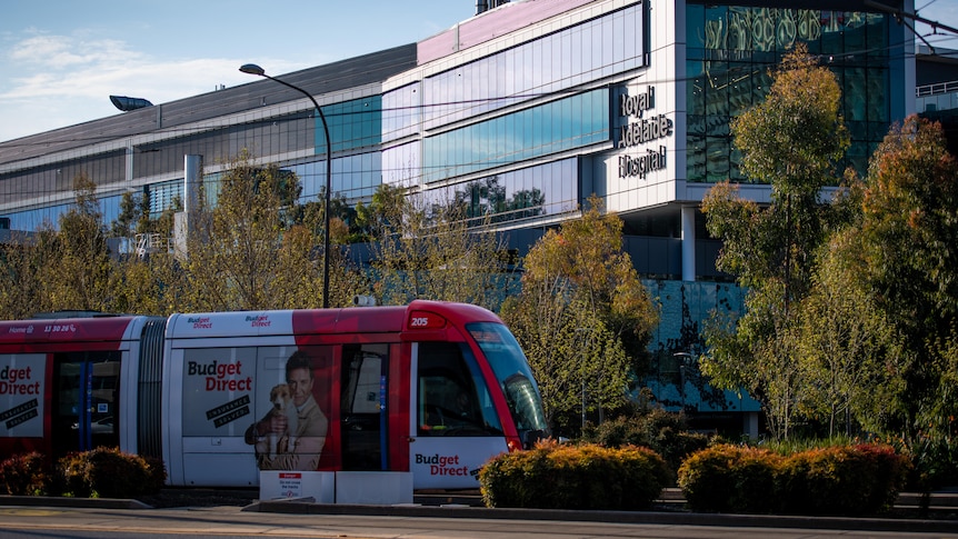 A tram trundles past a hospital