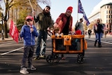 A family stands on a street with trump flags and children in a stroller