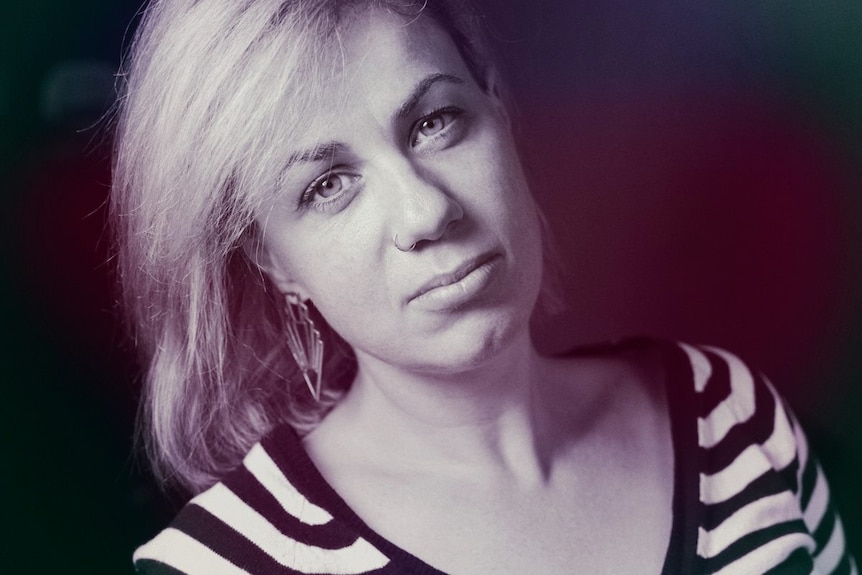 A woman with blonde hair and wearing a black-and-white striped shirt.