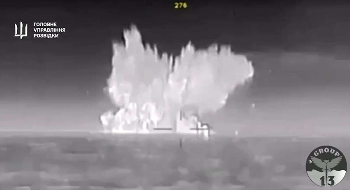 Black and white footage at sea that appears to show an explosion in the distance.