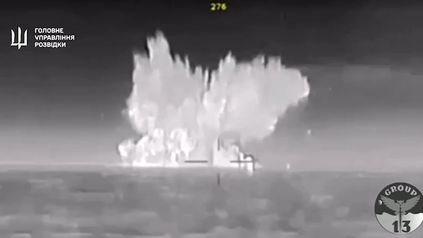 Black and white footage at sea that appears to show an explosion in the distance.