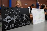 Children with signs that read 'SAVE REDFERN YOUTH CONNECT' at the National Centre of Indigenous Excellence