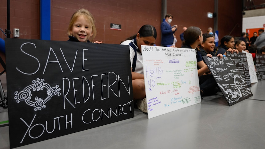 Children with signs that read 'SAVE REDFERN YOUTH CONNECT' at the National Centre of Indigenous Excellence