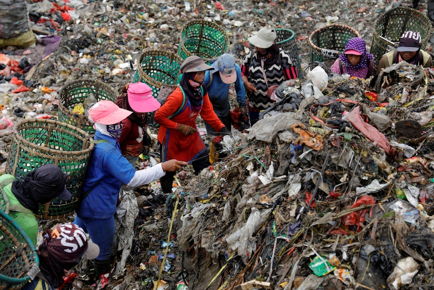 A group of scavengers search for items and plastics in a landfill. 