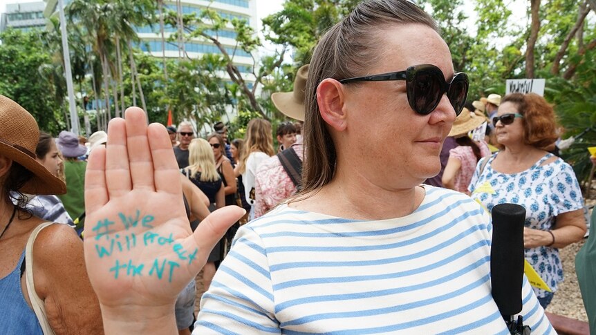 A woman has "#We will protect the NT" written on her palm