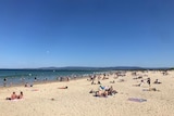 people lie on a beach under blue skies