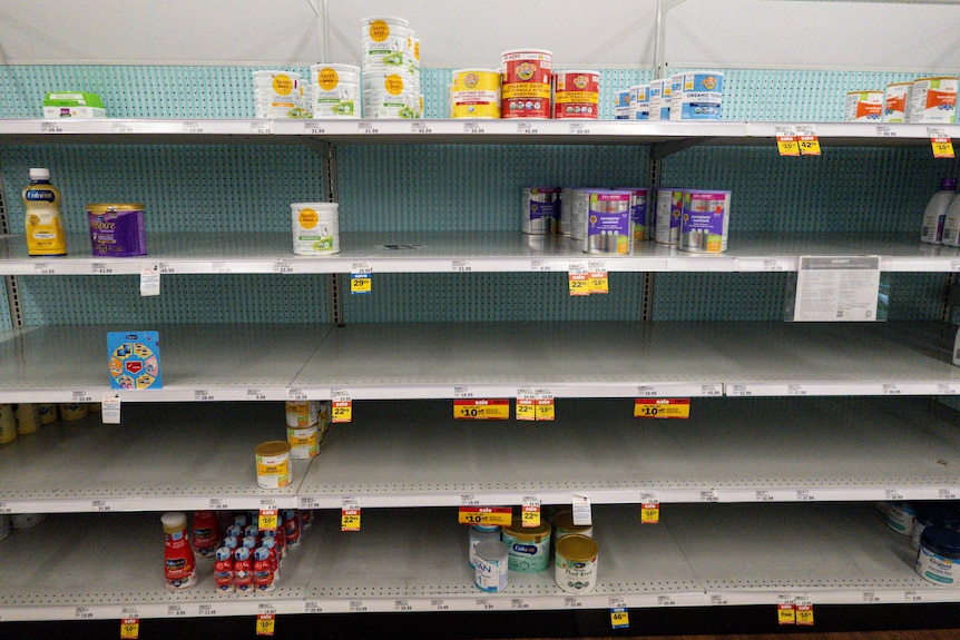 Una fila de estantes en un supermercado de EE. UU., con solo unas pocas latas de fórmula para bebés en exhibición 