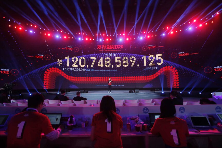 Attendants sit in front of a giant screen showing the total sales figure of 120,748,589,125 yuan for its "Singles' Day" sale
