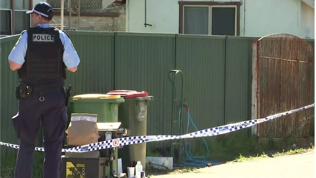 police stand outside a house near garbage bins as they investigate the bashing of a child 