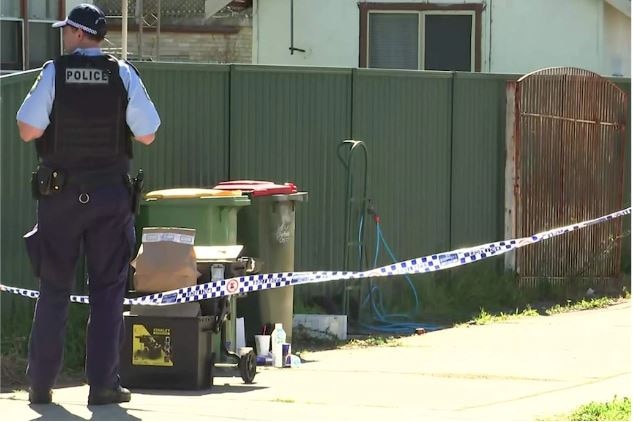 police stand outside a house near garbage bins as they investigate the bashing of a child 
