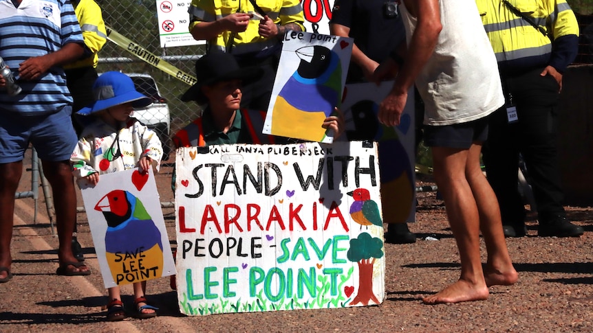 a child next to a sign saying 'stand with larrakia people, save lee point'