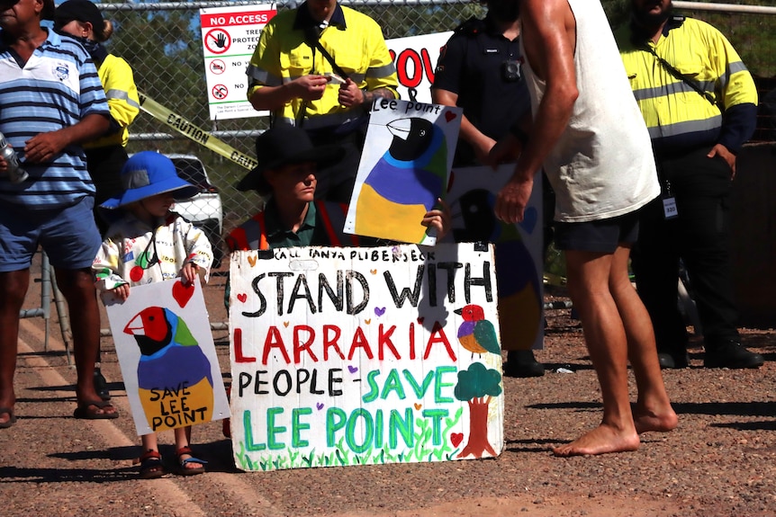 a child next to a sign saying 'stand with larrakia people, save lee point'