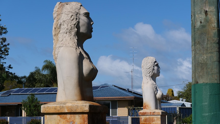 Two large sculptures on the side of the road, the sculptures are of half naked women.