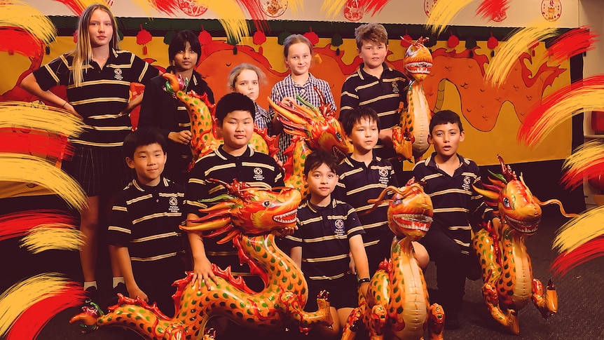 A group of 10 students hold inflatable dragons while posing for a photo.