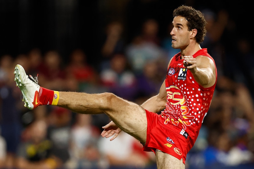A Gold Coast Suns AFL player kicks the ball with his right foot.