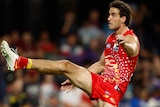A Gold Coast Suns AFL player kicks the ball with his right foot.