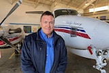 Man stands in front of Royal Flying Doctor Service plane